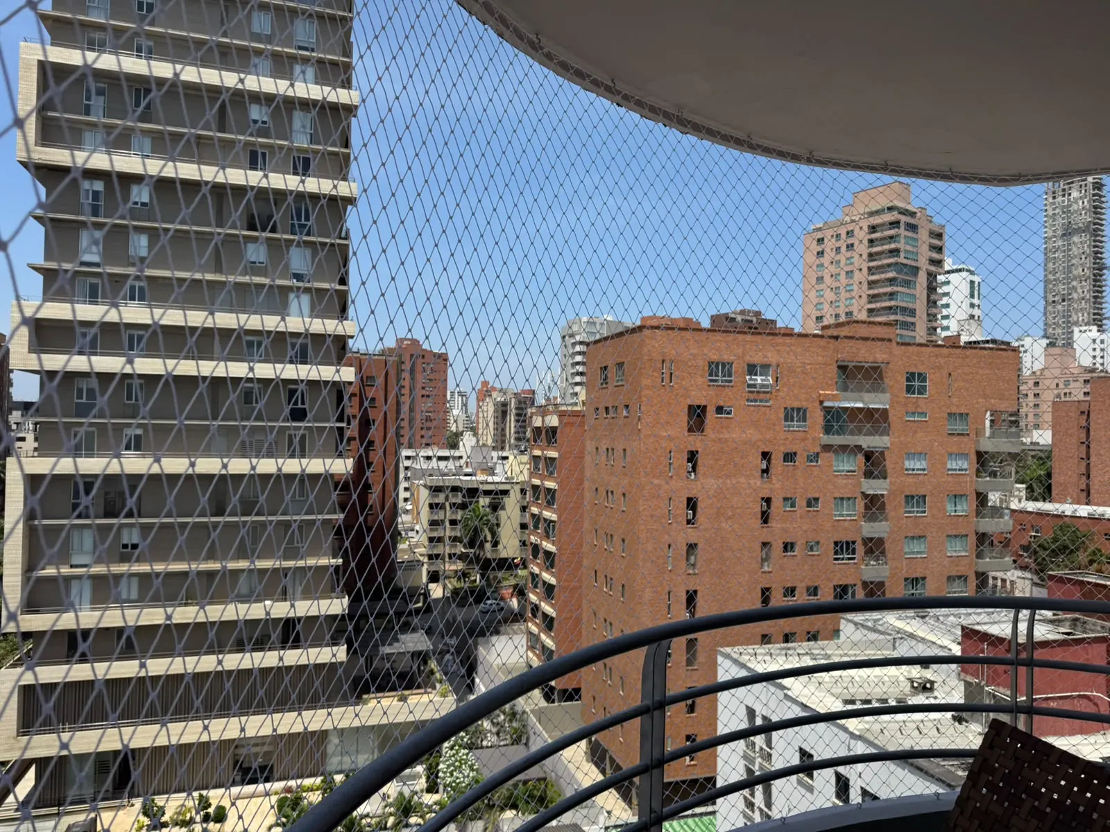 Balcón curvo con malla de seguridad en buen estado y vista a la ciudad